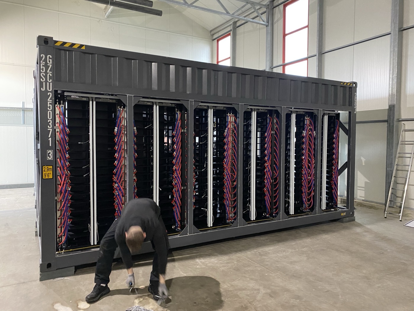 Conteneur serveur K51 avec refroidissement liquide — les tuyaux rouges et bleus transportent la chaleur vers les serres